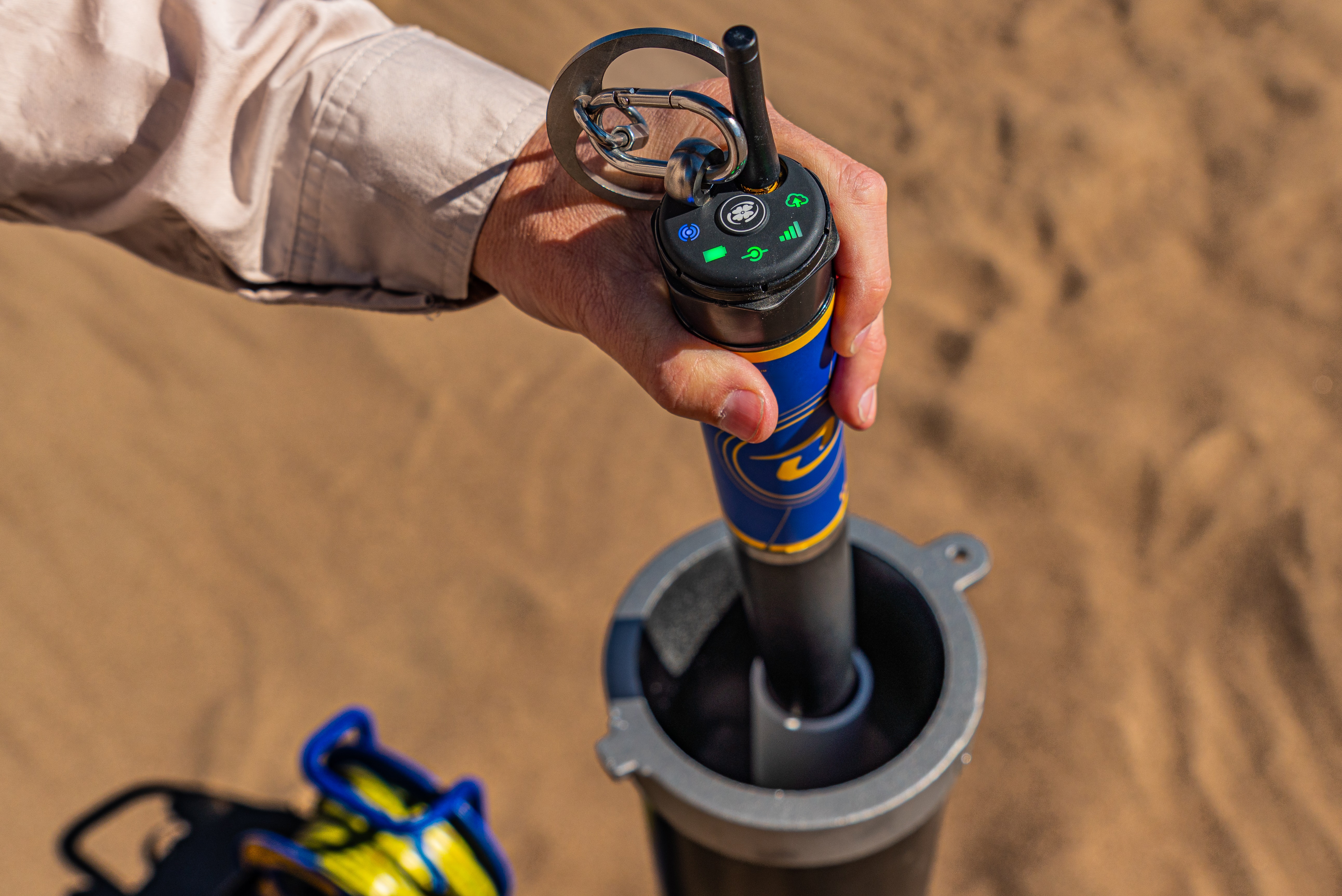 A device going into a well while the hand is putting it into the well.