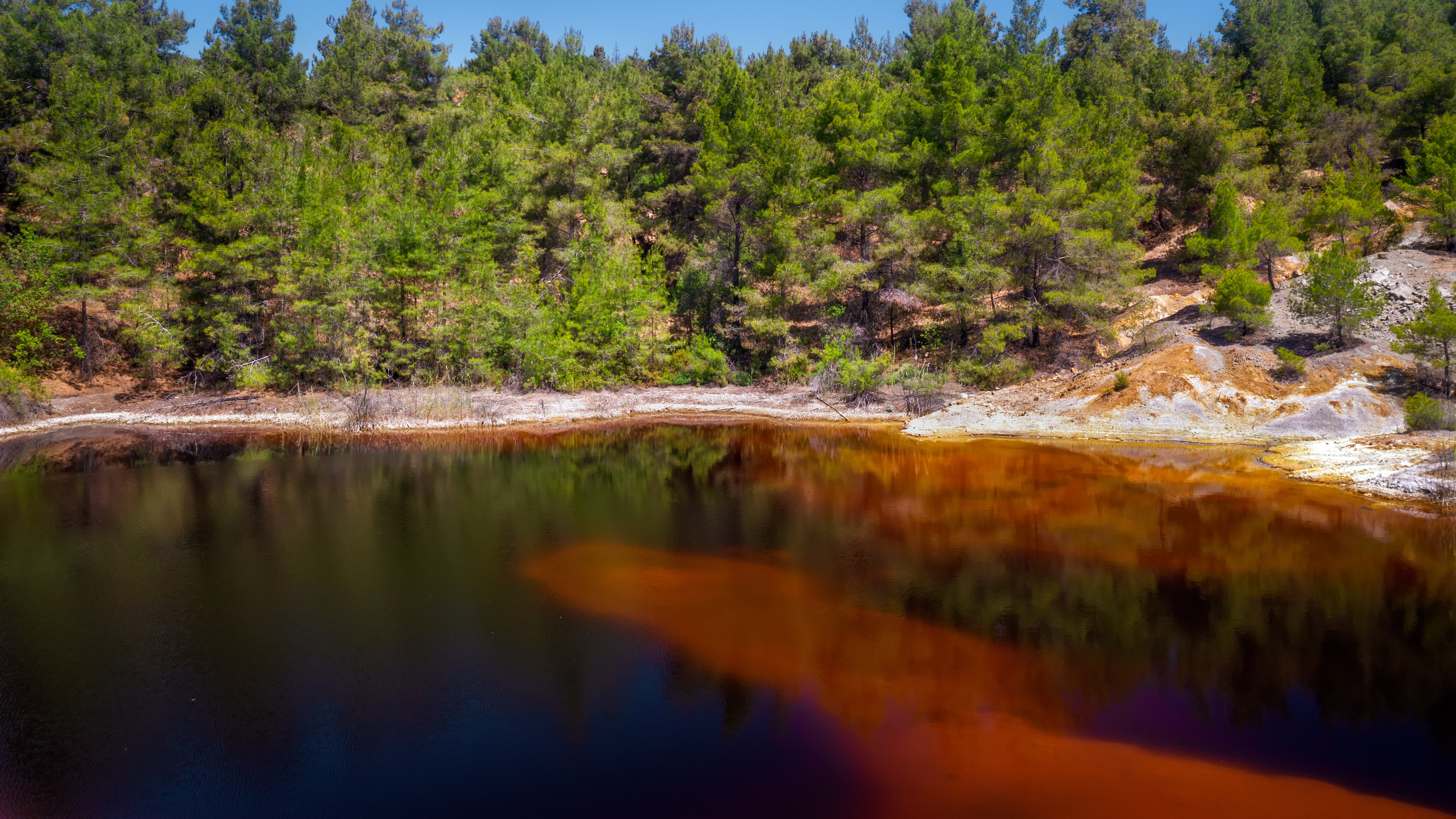 Shore of toxic red lake in abandoned open pit mine. Its color derives from high levels of acid and heavy metals