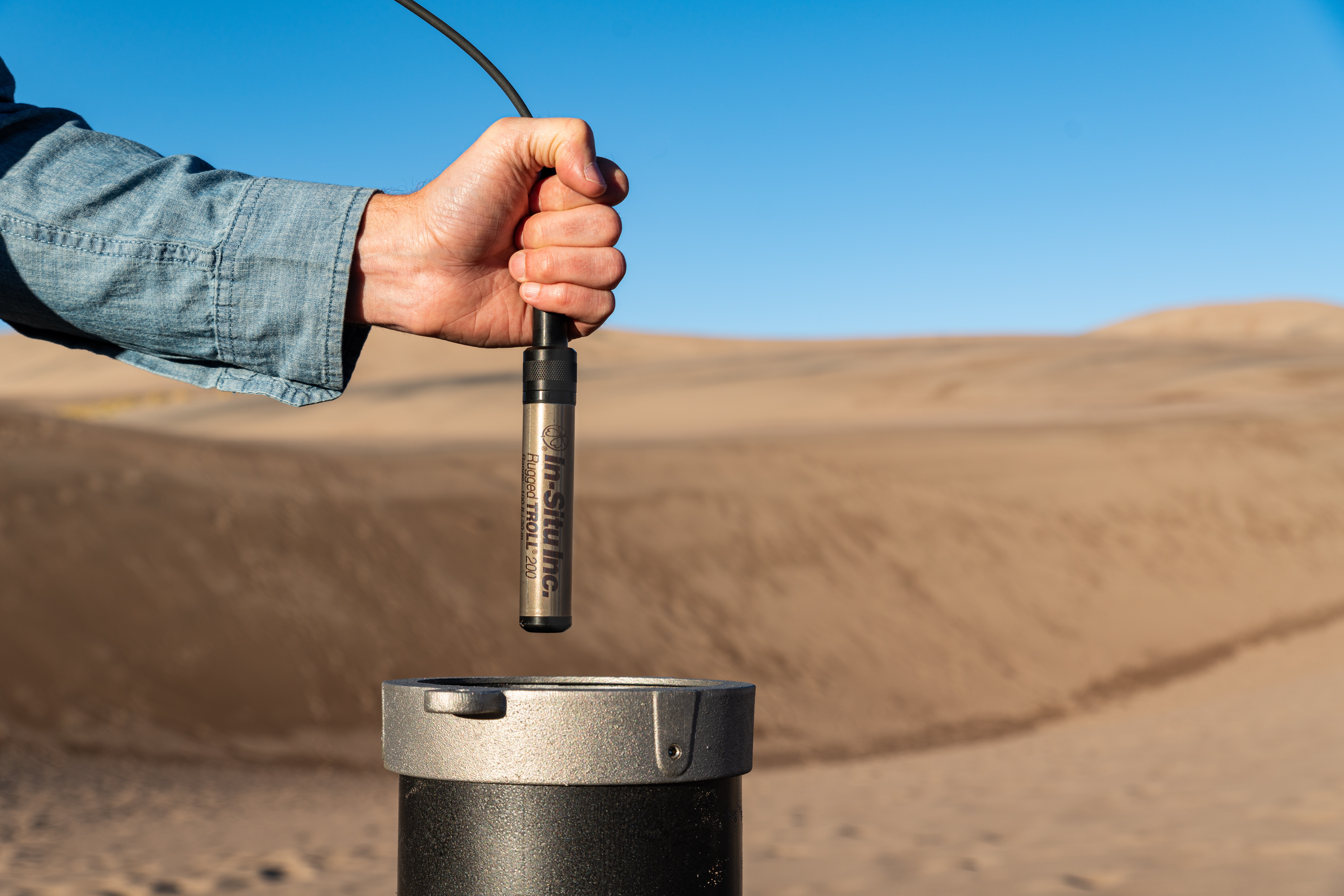 A hand over a well in the desert.