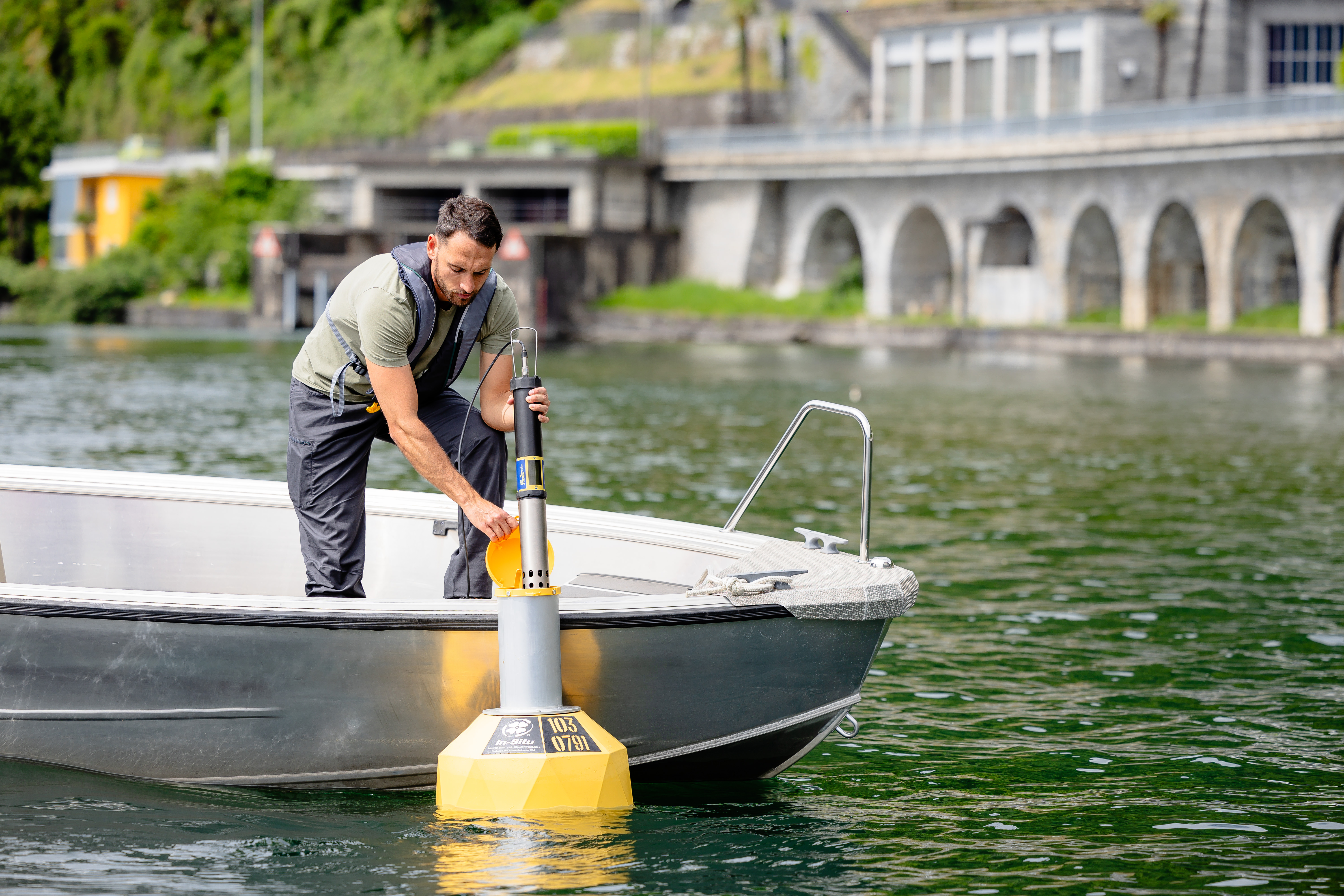 A guy putting a device inside a yellow buoy