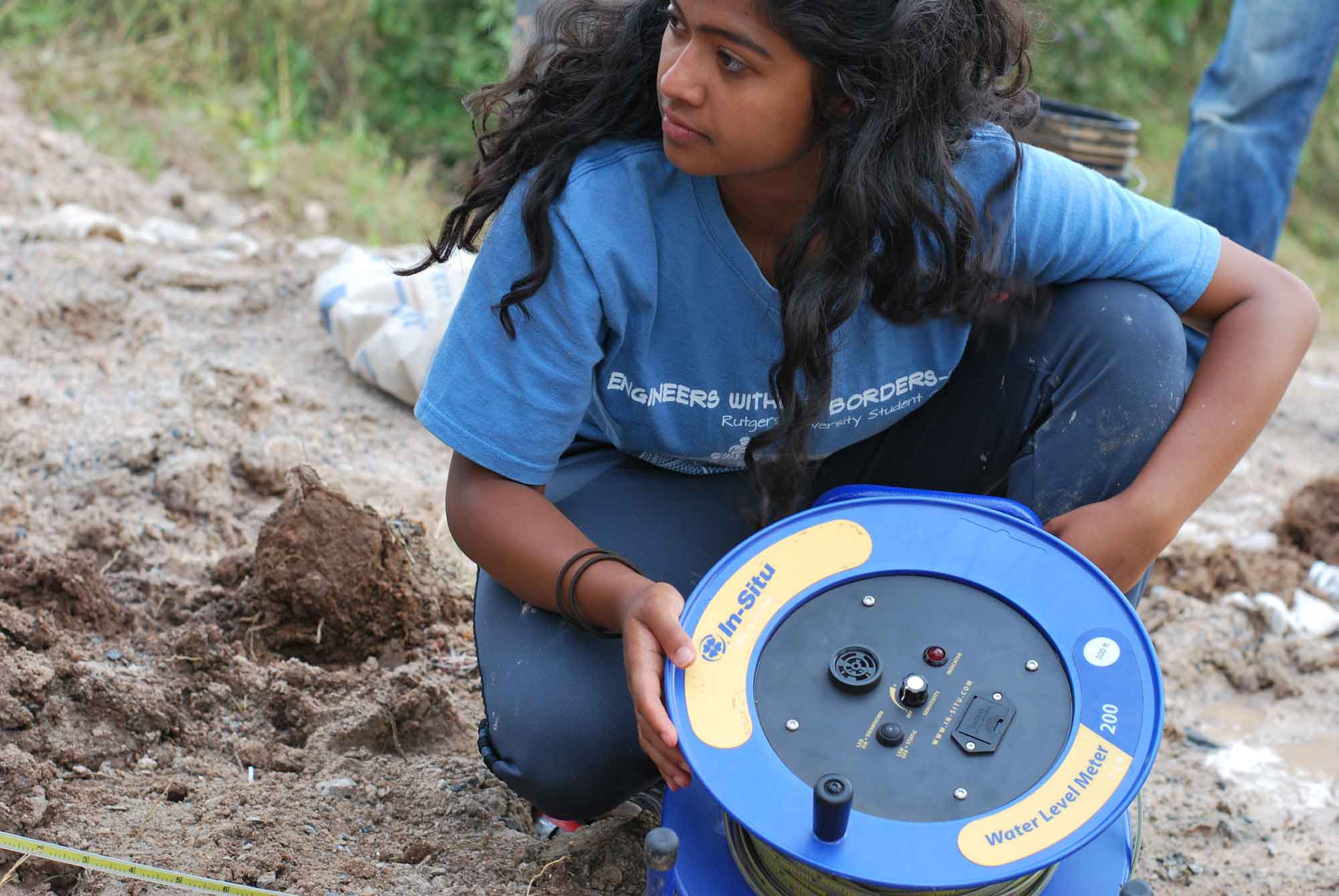 W girl holding a blue and yellow wheel near mud.